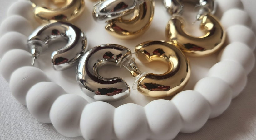 beyaz bir tabağın içinde silver ve gold renkli çelik küpeler var